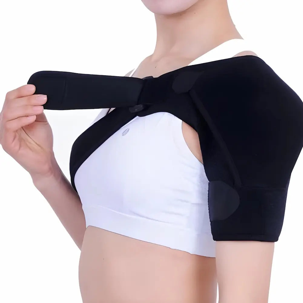 A imagem mostra uma pessoa vestindo um suporte ortopédico preto no ombro. A pessoa, vestida com uma blusa branca, está ajustando a faixa do suporte sobre o ombro direito. O suporte cobre o ombro e se ajusta com tiras ao redor do peito. A expressão da pessoa não é visível.
